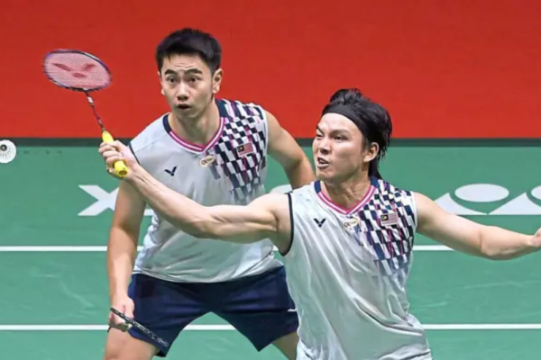 Malaysian men's doubles pair Goh Sze Fei and Nur Izzuddin Rumsani in action on the badminton court, mid-rally during their Thomas Cup match against Finland.