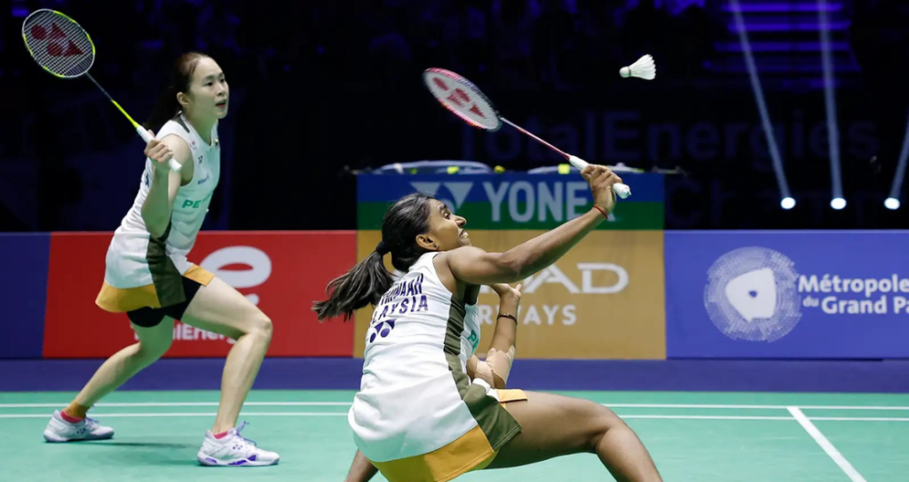 Pearly-Thinaah court defense showing M Thinaah lunging extremely low to return a shuttlecock on the green court.
