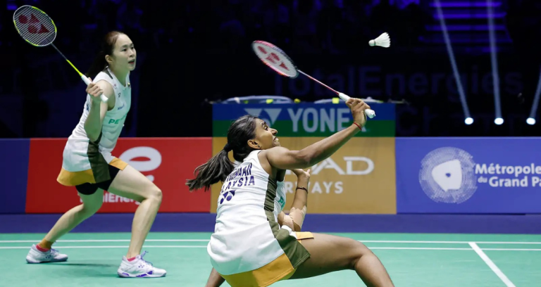 Pearly-Thinaah court defense showing M Thinaah lunging extremely low to return a shuttlecock on the green court.