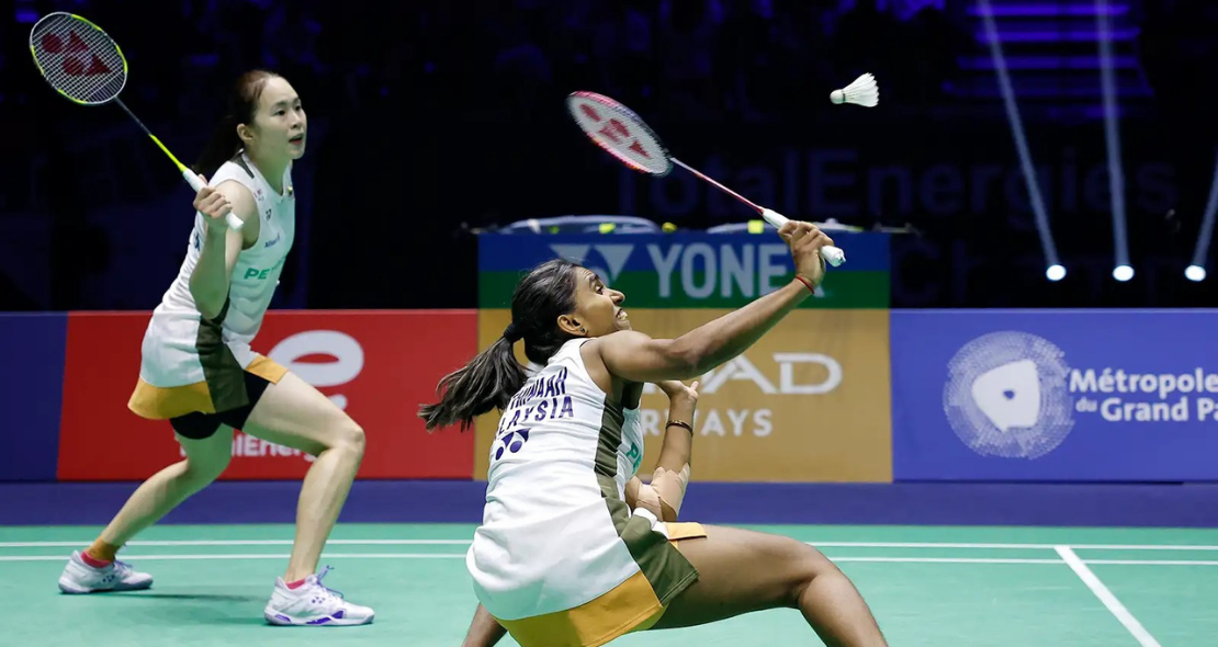 Pearly-Thinaah court defense showing M Thinaah lunging extremely low to return a shuttlecock on the green court.