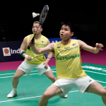 Aaron-Wooi Yik Worlds Final showing Soh Wooi Yik crouching low at the net with Aaron Chia watching in the background.