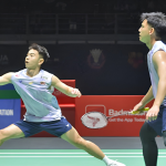 Sze Fei-Izzuddin History Target showing Goh Sze Fei lunging low on court with Nur Izzuddin Rumsani watching.