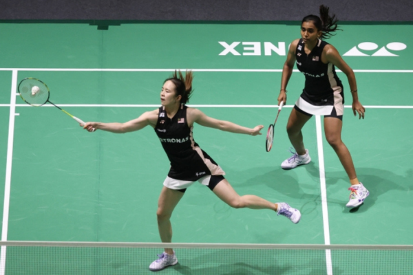 Pearly-Thinaah Shenzhen Campaign showing Pearly Tan lunging low on court with M Thinaah watching in the background.
