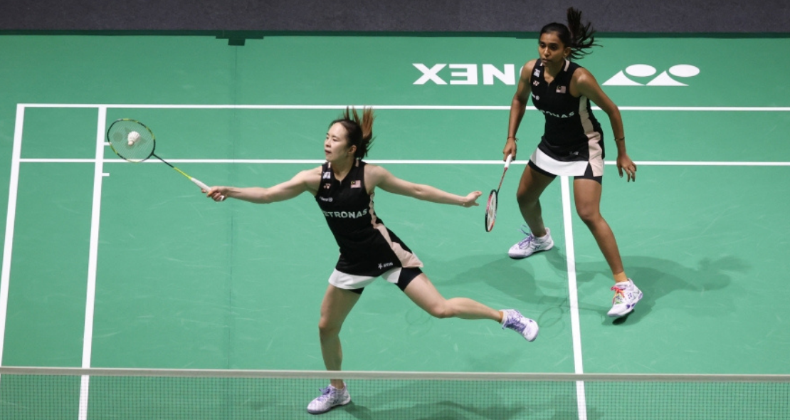 Pearly-Thinaah Shenzhen Campaign showing Pearly Tan lunging low on court with M Thinaah watching in the background.