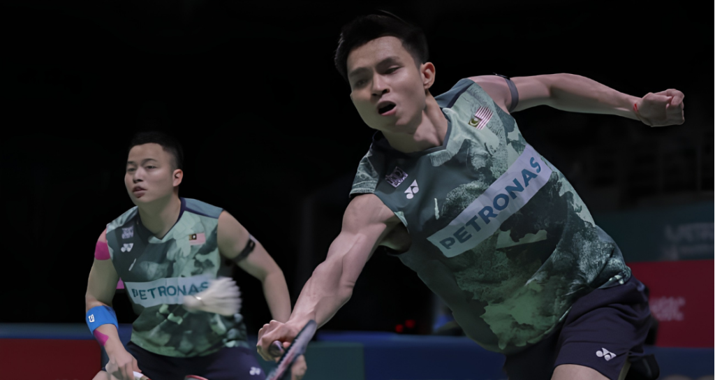 Soh Wooi Yik lunges forward to return a shot while partner Aaron Chia stays alert in their dark green Petronas jerseys.