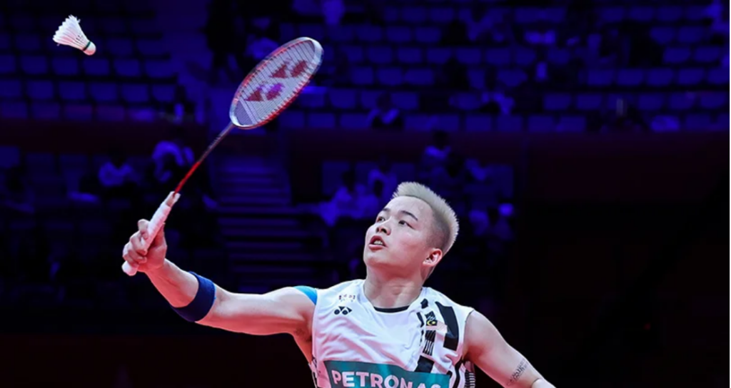Aaron Chia tracks the shuttlecock overhead to execute a smash in his white Petronas Malaysian national jersey.