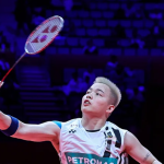 Aaron Chia tracks the shuttlecock overhead to execute a smash in his white Petronas Malaysian national jersey.