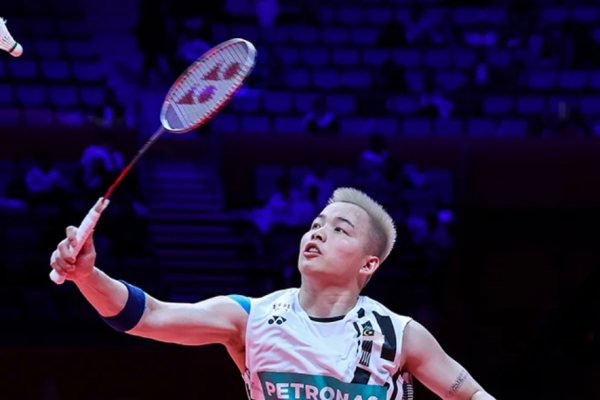 Aaron Chia tracks the shuttlecock overhead to execute a smash in his white Petronas Malaysian national jersey.