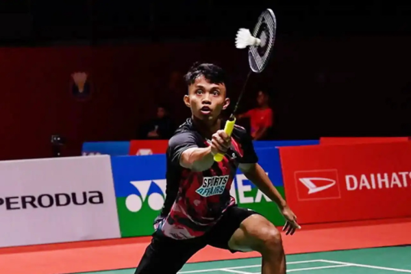 Aidil Sholeh Ali Sadikin lunges forward to execute a forehand net return in his black and red jersey during a match.