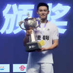 Cheam June Wei poses on the podium holding the silver trophy, gold medal, and championship prize money check at the 2026 Lin Dan Cup in Jincheng, China.