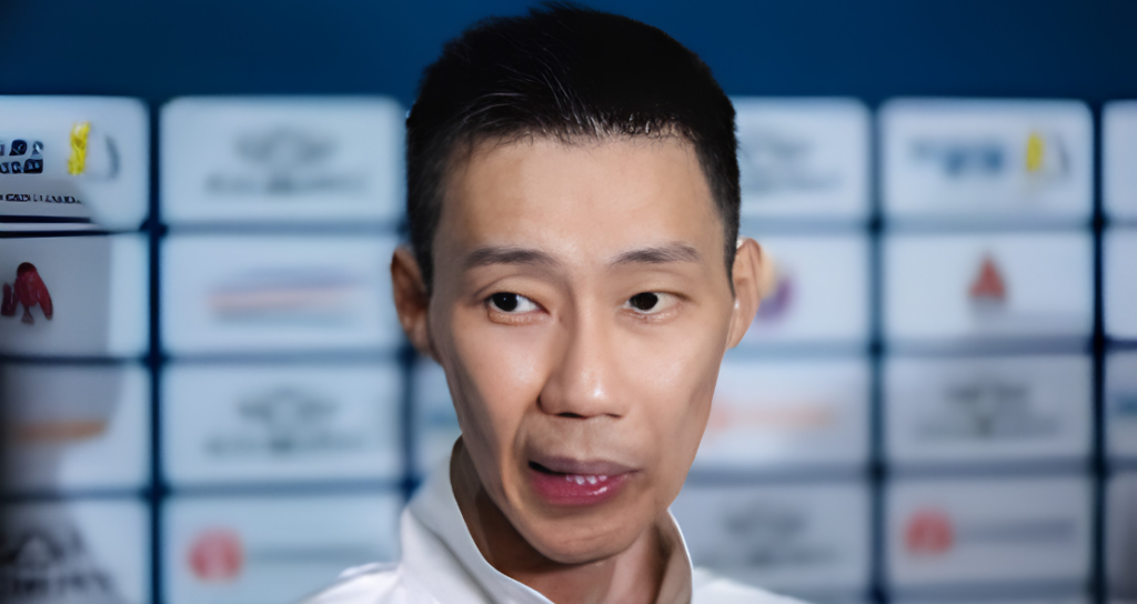 Lee Chong Wei speaks to journalists during a media interview in front of a tournament sponsor backdrop