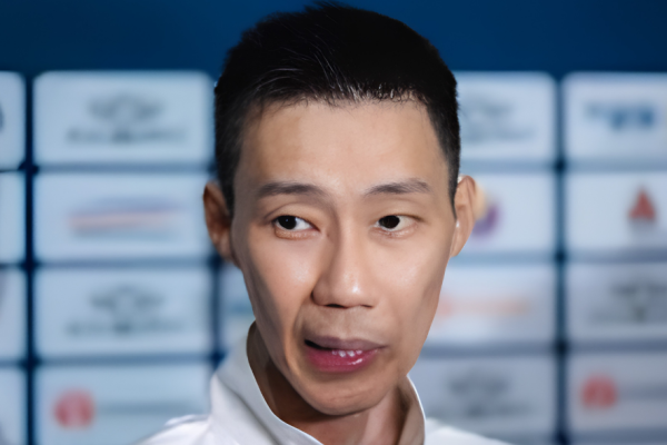 Lee Chong Wei speaks to journalists during a media interview in front of a tournament sponsor backdrop