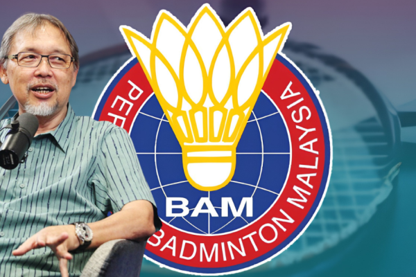 Razif Sidek speaks into a microphone during an interview beside the Badminton Association of Malaysia logo.