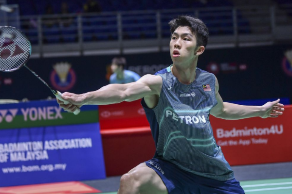 Eogene Ewe lunges forward to execute a backhand net shot in his teal Petronas Malaysian national jersey.