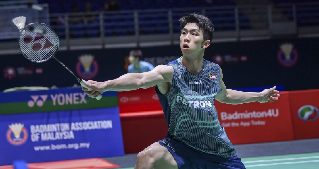 Eogene Ewe lunges forward to execute a backhand net shot in his teal Petronas Malaysian national jersey.