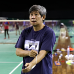Herry Iman Pierngadi oversees a training session in his navy Yonex t-shirt on the badminton court.