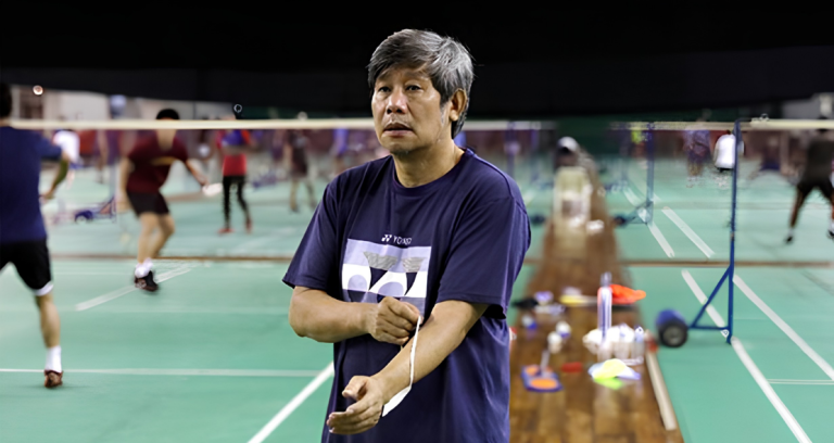 Herry Iman Pierngadi oversees a training session in his navy Yonex t-shirt on the badminton court.