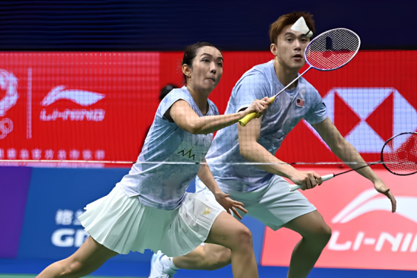 Lai Pei Jing lunges low at the net while Hoo Pang Ron tracks the shuttlecock in their light blue Malaysian kits.