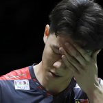 Lee Zii Jia covers his face in disappointment wearing his Malaysian national team jersey after a tough match.