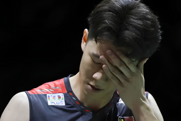Lee Zii Jia covers his face in disappointment wearing his Malaysian national team jersey after a tough match.