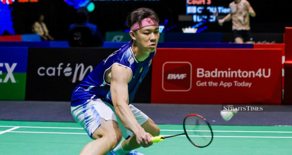 Lee Zii Jia lunges low to execute a delicate forehand net return in his blue Malaysian jersey and pink headband