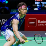 Lee Zii Jia lunges low to execute a delicate forehand net return in his blue Malaysian jersey and pink headband