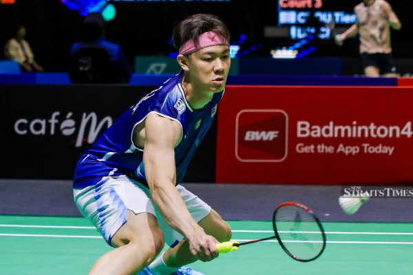 Lee Zii Jia lunges low to execute a delicate forehand net return in his blue Malaysian jersey and pink headband