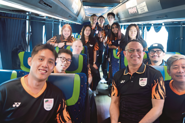 Rexy Mainaky and Malaysian national badminton players smile together inside the team bus during their Asian Games journey.