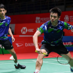 Tan Wee Kiong lunges forward at the net while partner Nur Mohd Azriyn Ayub stays alert in the back court in their blue Malaysian jerseys.