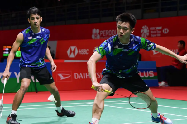 Tan Wee Kiong lunges forward at the net while partner Nur Mohd Azriyn Ayub stays alert in the back court in their blue Malaysian jerseys.