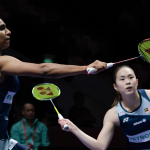 M. Thinaah lunges forward at the net while partner Pearly Tan maintains a defensive ready stance in their Malaysian jerseys during the Asian Games.