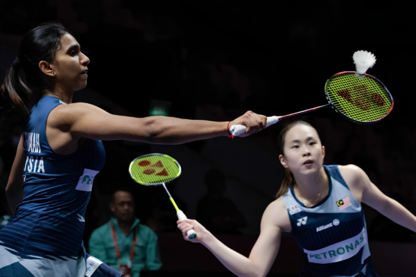 M. Thinaah lunges forward at the net while partner Pearly Tan maintains a defensive ready stance in their Malaysian jerseys during the Asian Games.
