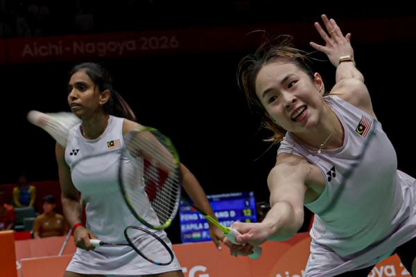 Pearly Tan lunges forward low at the net while M. Thinaah provides back-court cover in their white Malaysian jerseys during the Asian Games.