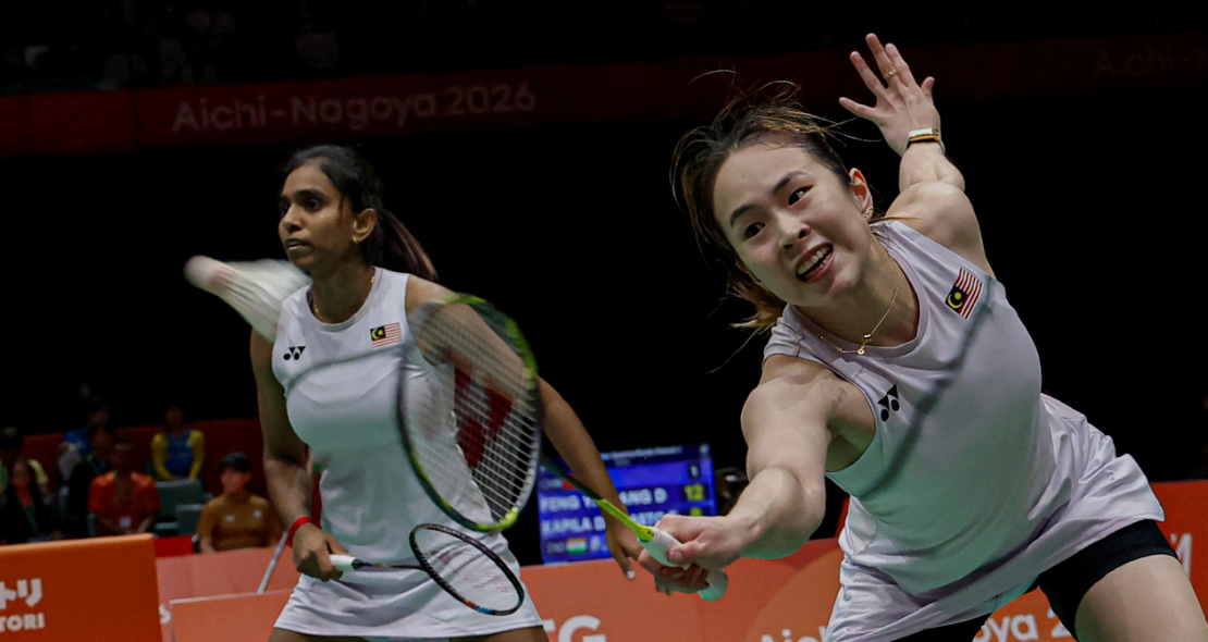 Pearly Tan lunges forward low at the net while M. Thinaah provides back-court cover in their white Malaysian jerseys during the Asian Games.