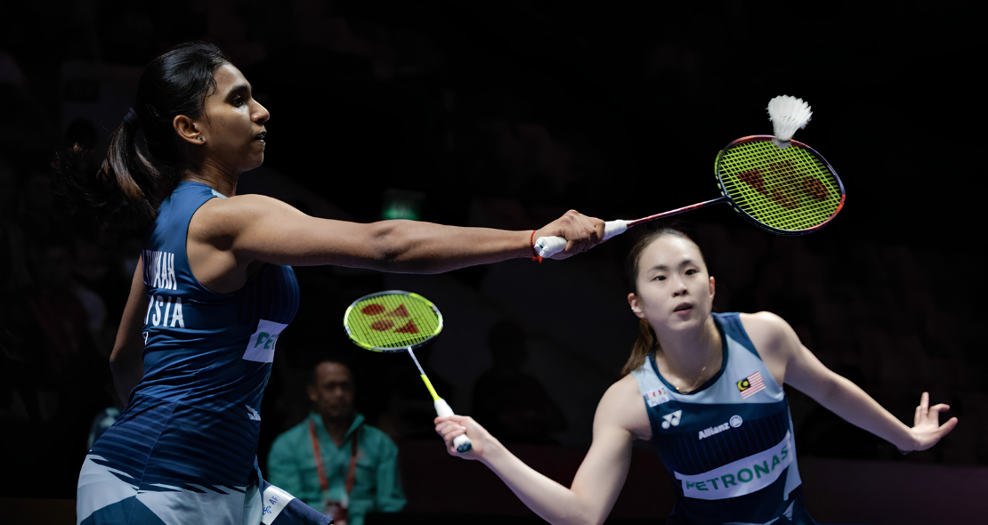 M. Thinaah lunges forward at the net while partner Pearly Tan maintains a defensive ready stance in their Malaysian jerseys during the Asian Games.