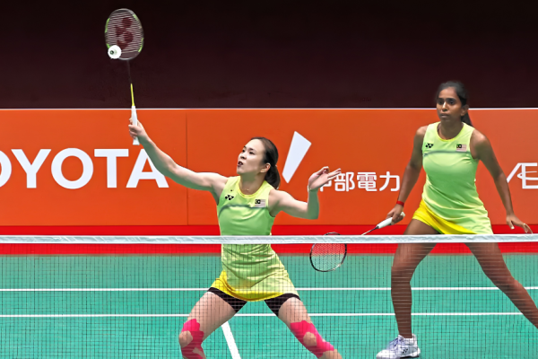 Pearly Tan intercepts the shuttlecock at the net while M. Thinaah guards the rear court in their lime green jerseys during the Asian Games quarterfinal against South Korea.