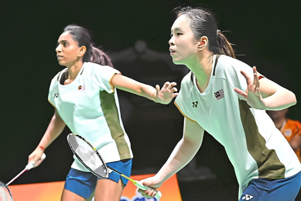Pearly Tan and M. Thinaah adopt a focused ready stance on court in their white Malaysian jerseys during a match.