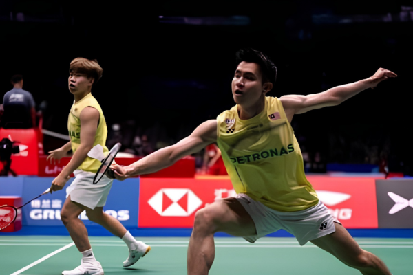 Soh Wooi Yik lunges forward at the net while partner Aaron Tai covers the back court in their yellow Malaysian national jerseys.