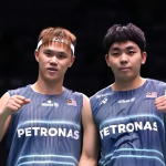 Tee Kai Wun and Yap Roy King pose on court in their navy blue Petronas Malaysia national team jerseys while celebrating with fist pumps.