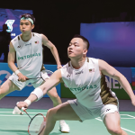 Aaron Chia lunges forward to return a shot while Soh Wooi Yik stays alert in their white Petronas jerseys.