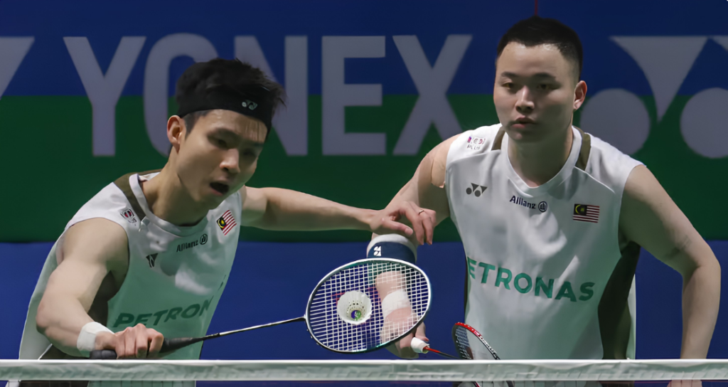 Soh Wooi Yik intercepts the shuttlecock at the net while Aaron Chia stays alert in their white Petronas jerseys.