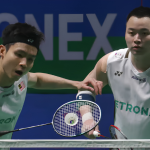 Soh Wooi Yik intercepts the shuttlecock at the net while Aaron Chia stays alert in their white Petronas jerseys.