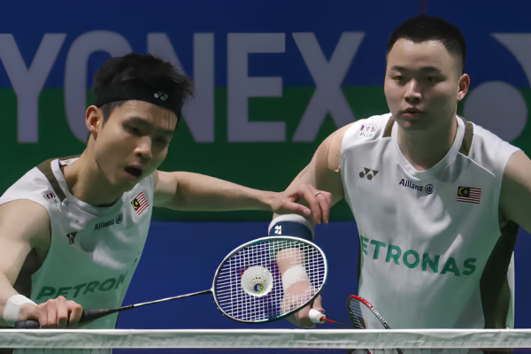 Soh Wooi Yik intercepts the shuttlecock at the net while Aaron Chia stays alert in their white Petronas jerseys.