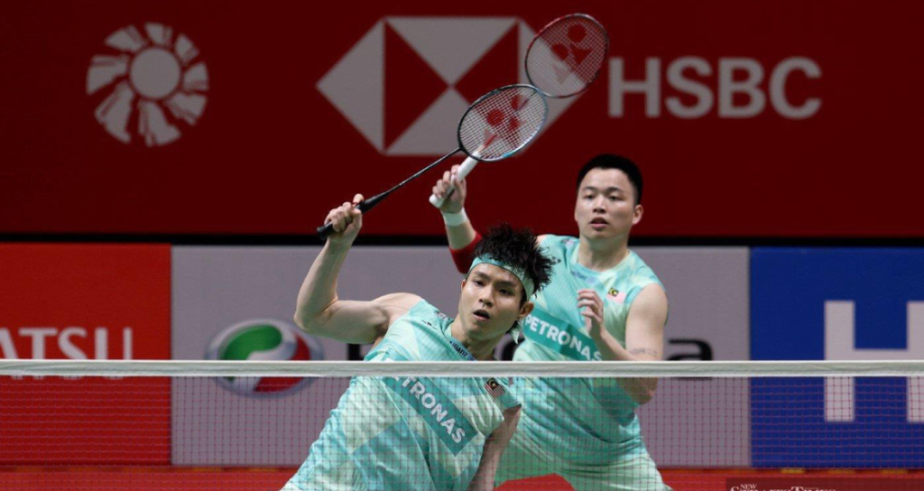 Soh Wooi Yik executes an overhead return at the net while Aaron Chia stays alert in their mint green Petronas jerseys.