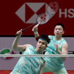Soh Wooi Yik executes an overhead return at the net while Aaron Chia stays alert in their mint green Petronas jerseys.