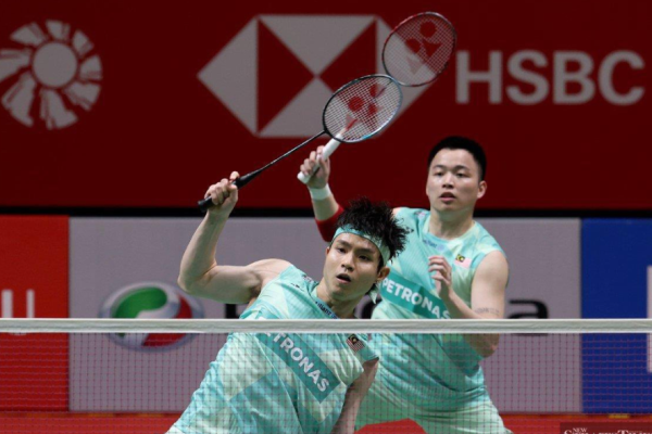 Soh Wooi Yik executes an overhead return at the net while Aaron Chia stays alert in their mint green Petronas jerseys.