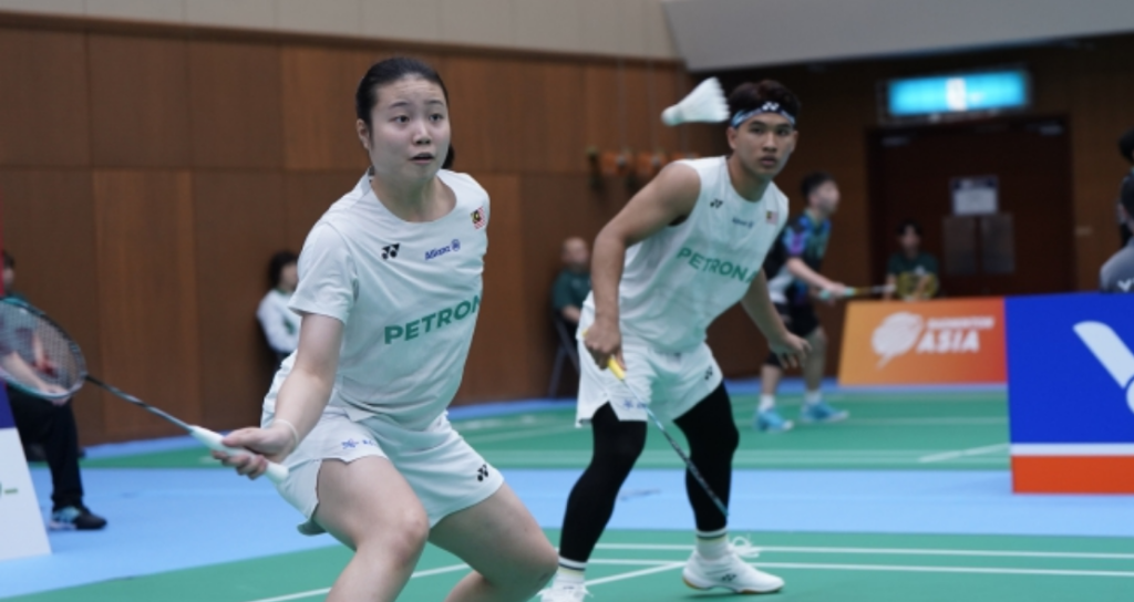 Low Zi Yu and Ahmad Redzuan Zulawaqqarizal adopt an alert defensive stance in their white Petronas jerseys during a mixed doubles match.