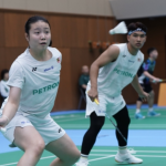 Low Zi Yu and Ahmad Redzuan Zulawaqqarizal adopt an alert defensive stance in their white Petronas jerseys during a mixed doubles match.