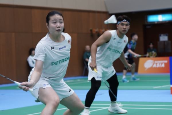 Low Zi Yu and Ahmad Redzuan Zulawaqqarizal adopt an alert defensive stance in their white Petronas jerseys during a mixed doubles match.