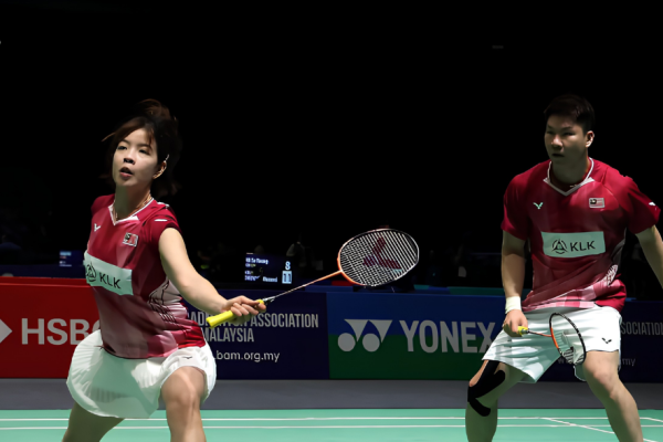 Shevon Lai Jemie executes a forehand return while Goh Soon Huat guards the back court in their red Malaysian jerseys.